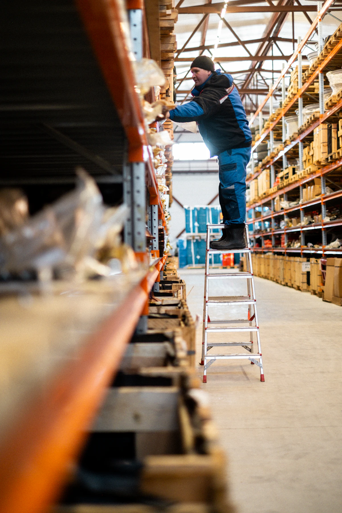 Warehouse worker organising inventory on a ladder